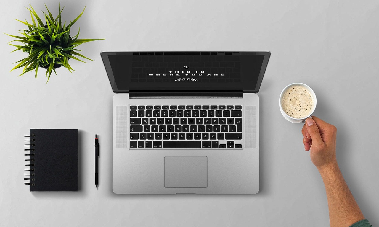 A customer reading email at their laptop with a coffee, the kind of steady note that brings past buyers back