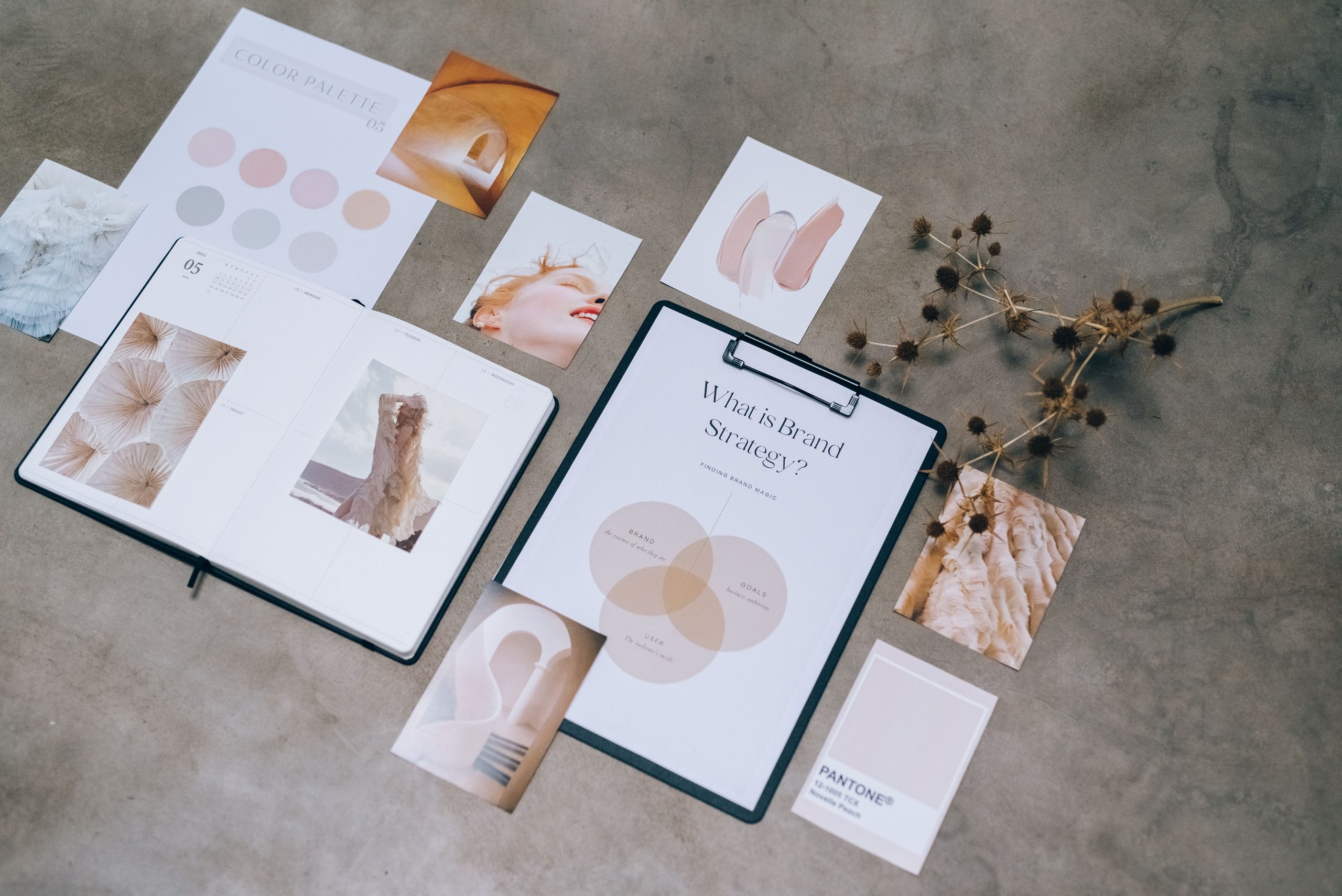 Brand design materials laid out on a desk with a color palette and moodboard, showing a consistent look across print and digital