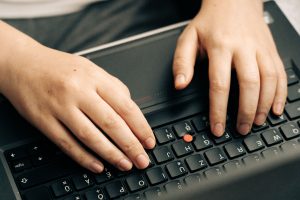 Close-up of hands typing on a laptop keyboard, the routine upkeep work behind ongoing website maintenance