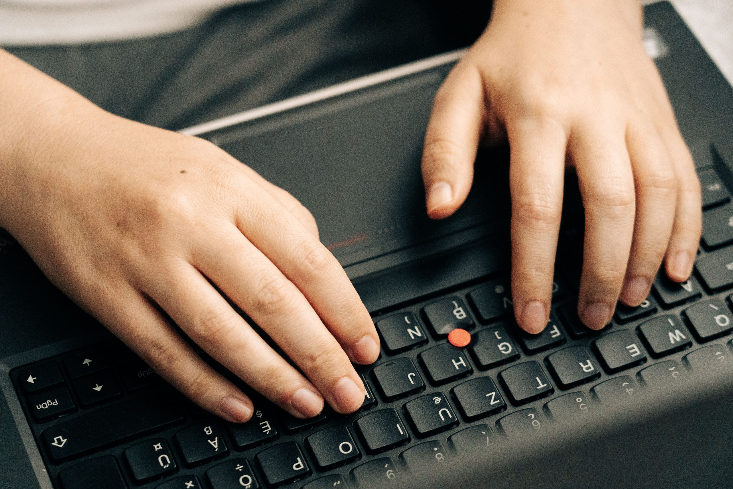 Close-up of hands typing on a laptop keyboard, the routine upkeep work behind ongoing website maintenance