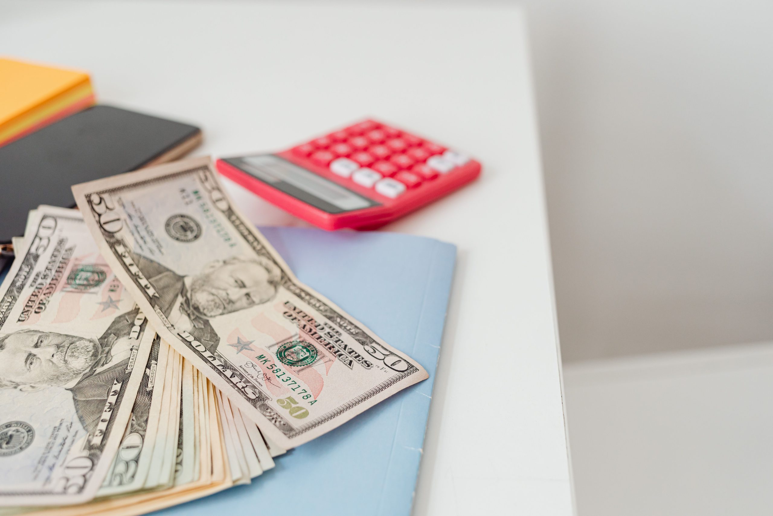 Notebook, cash and a calculator on a desk, used for working out what a small business website will cost